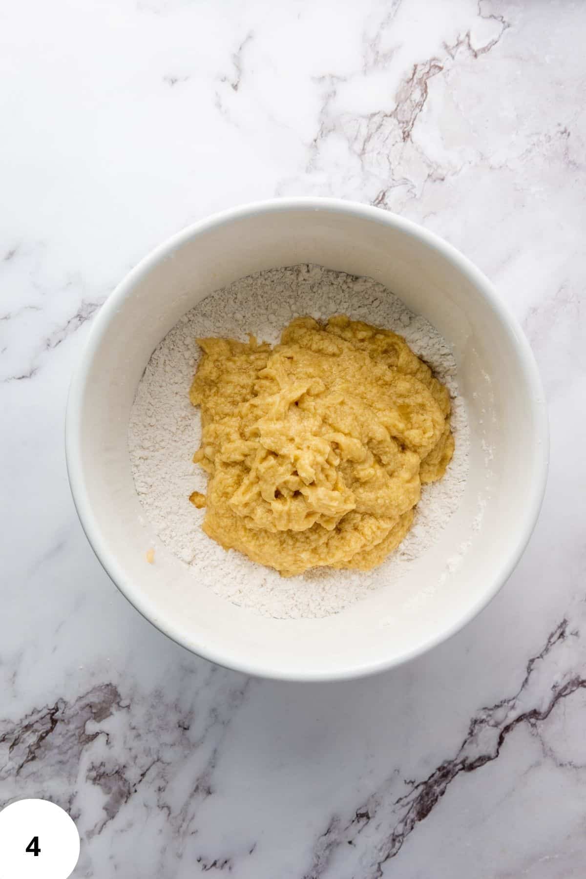 Cookie ingredients being mixed in a bowl with a spatula resting on the side.
