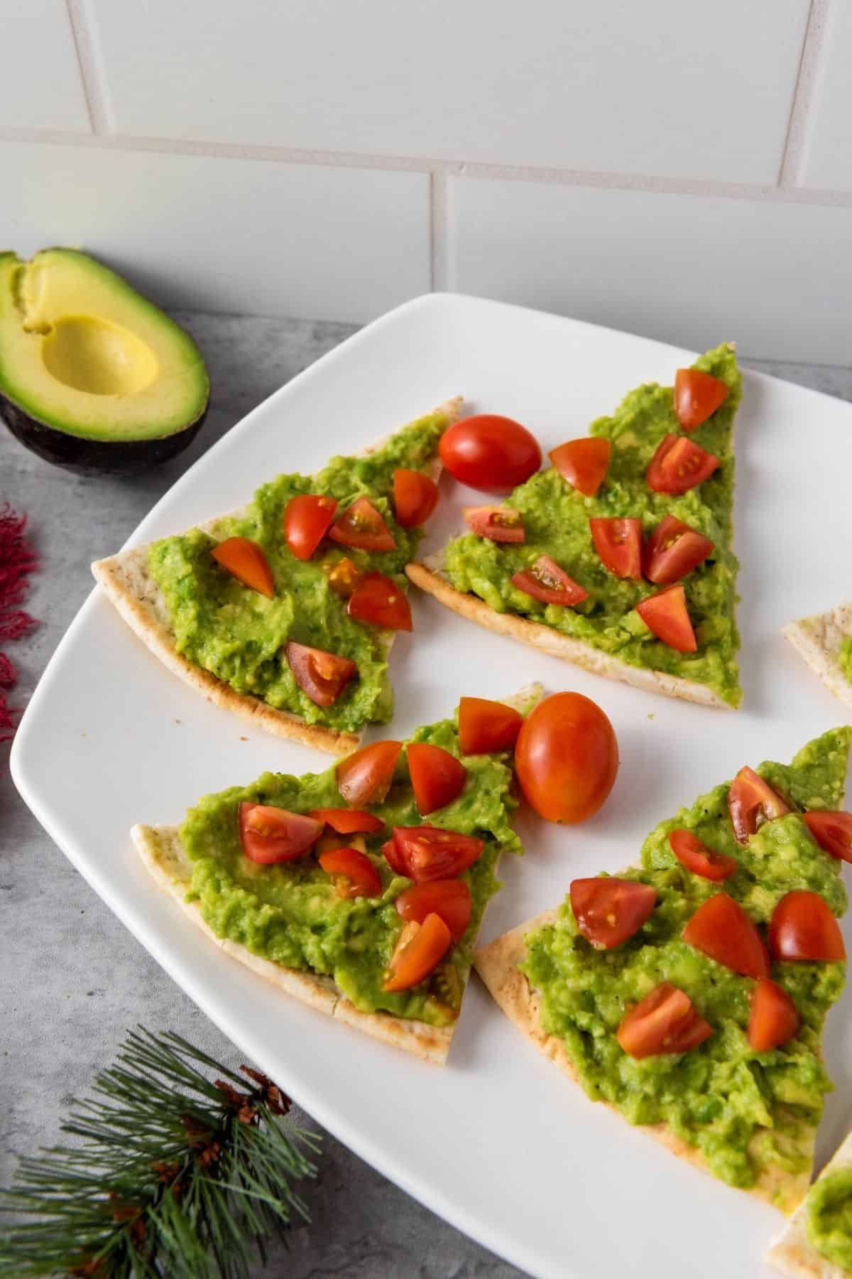 Arranged avocado pita trees in the plate with slice of avocado on the side.