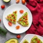 Avocado pita tree on a plate with cherry tomatoes and avocado, set with festive holiday decorations in the background.