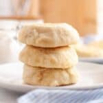 Stack of golden sourdough English muffins served on a plate with a cloth napkin underneath.