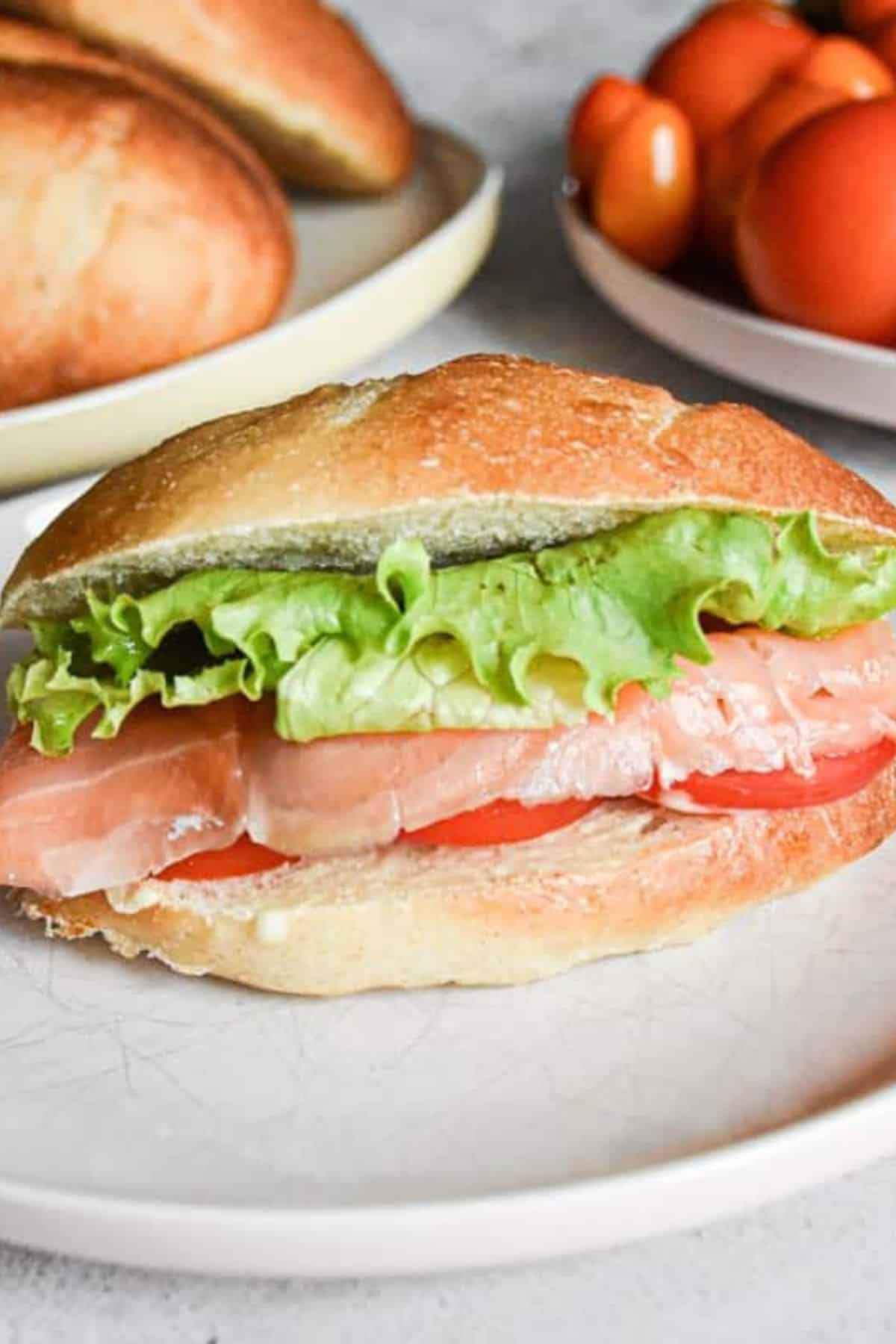 Ham sandwich with fresh green leaf served on a plate.