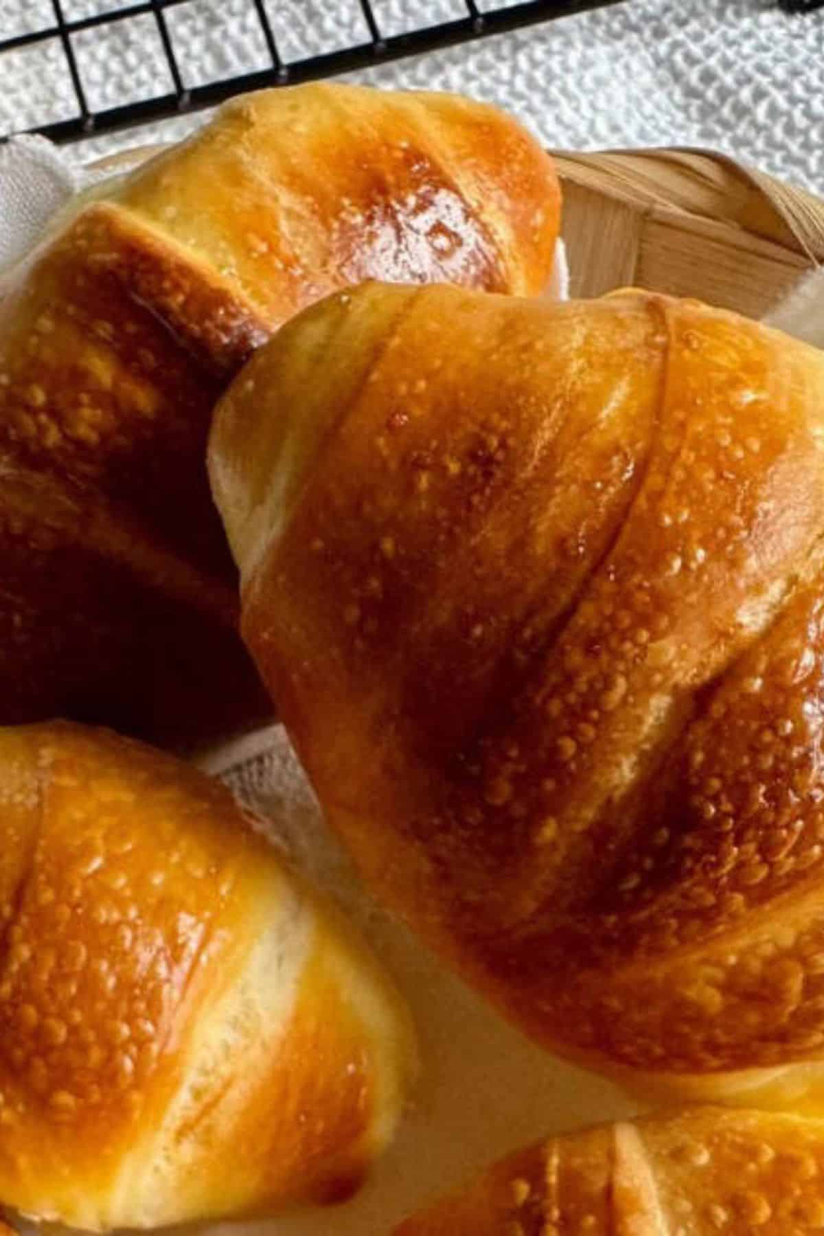 Close-up of soft sourdough crescent rolls in a basket.