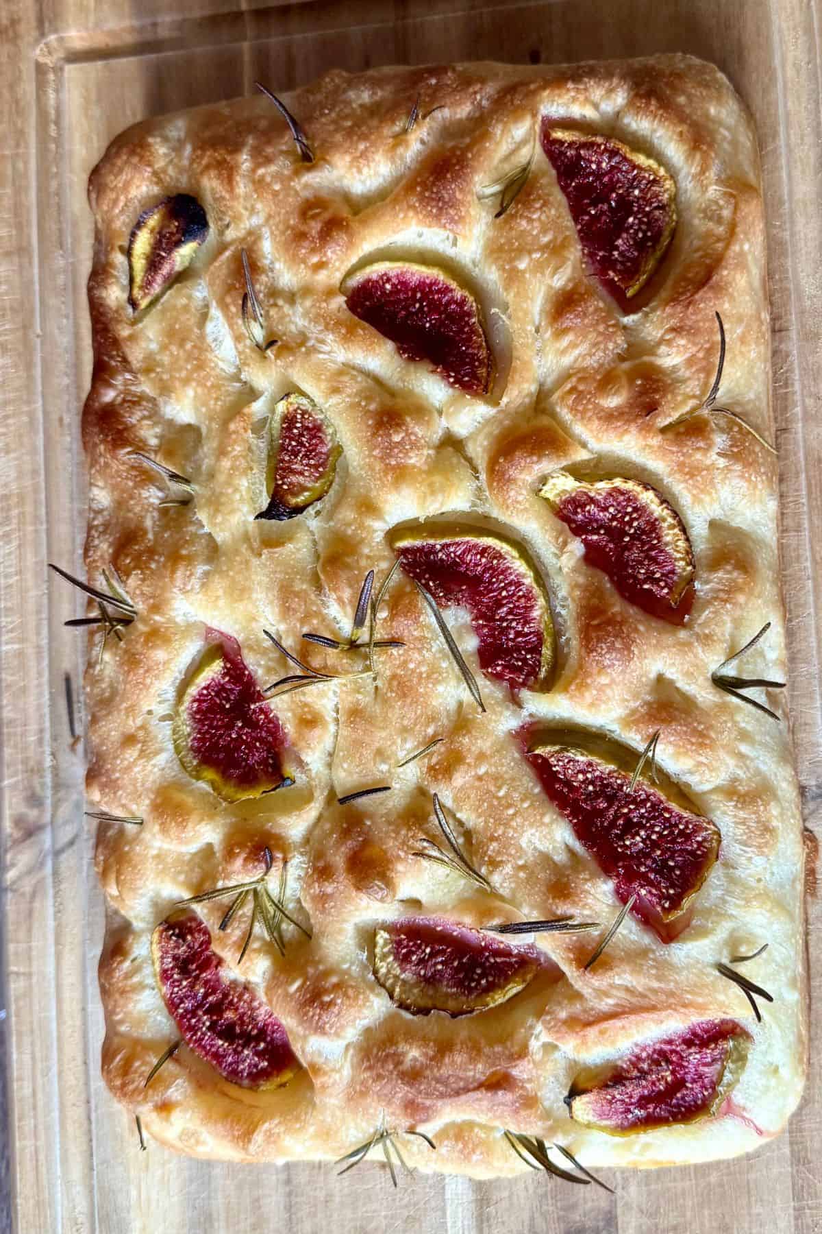 Freshly baked sourdough focaccia on a wooden cutting board.