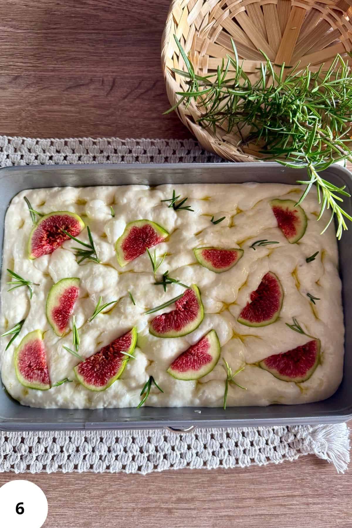 Sourdough bread topped with figs and rosemary in a baking pan ready to bake.