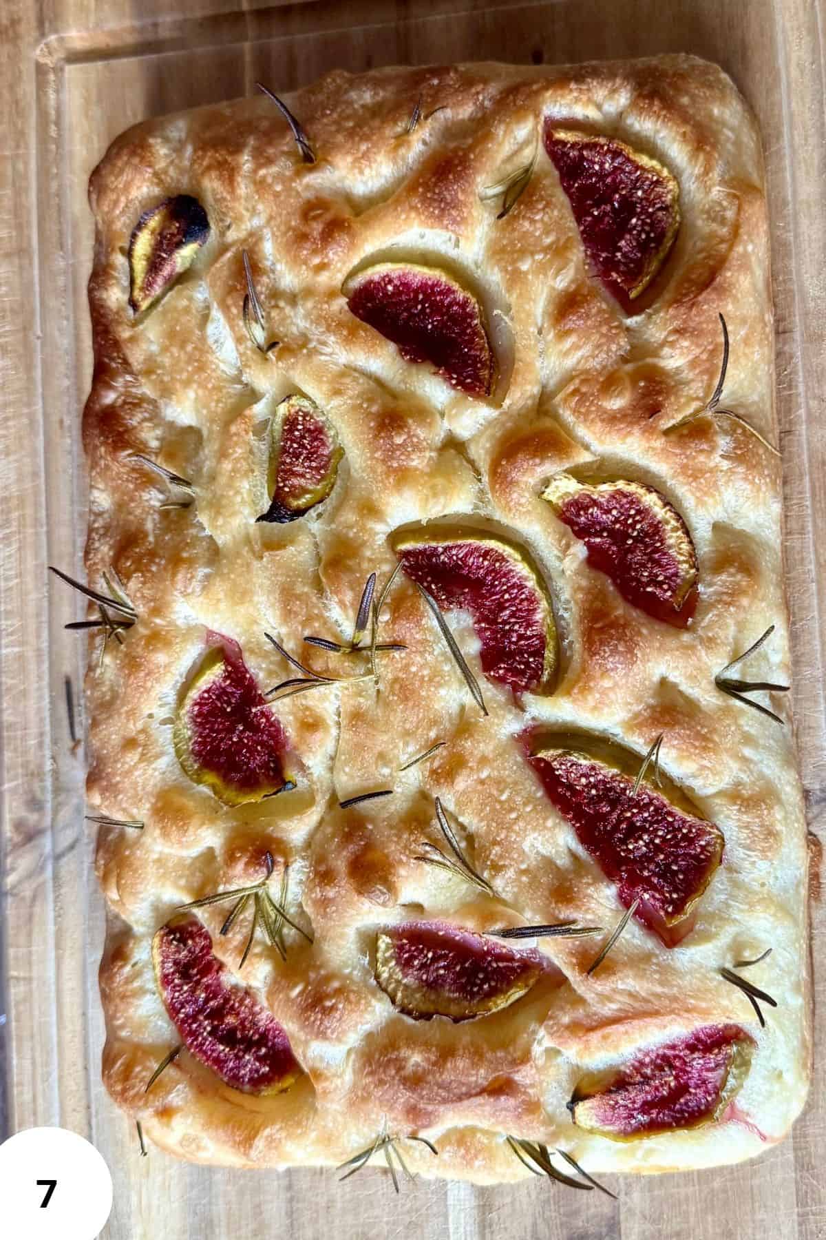 Freshly baked sourdough bread being placed onto a wooden board.
