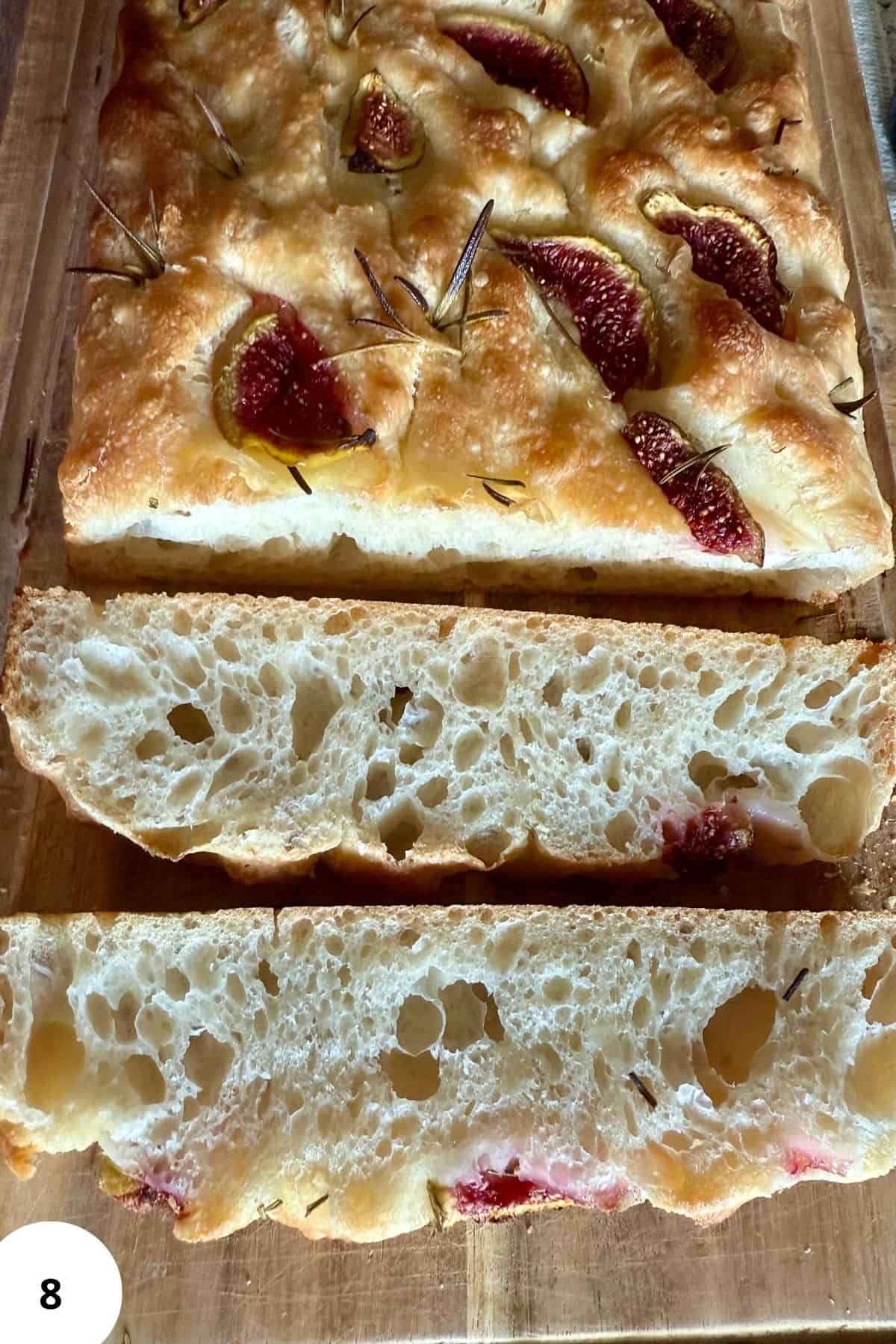 Freshly baked sourdough bread sliced and placed on a wooden board.