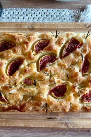 Freshly baked sourdough bread being placed onto a wooden board.