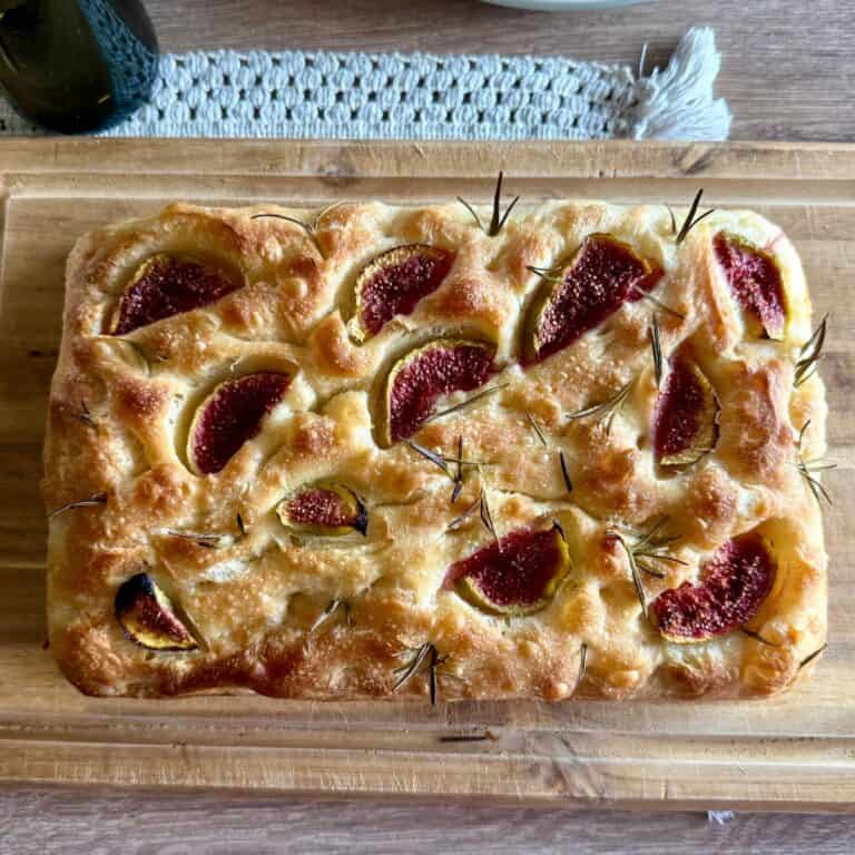 Freshly baked sourdough bread being placed onto a wooden board.