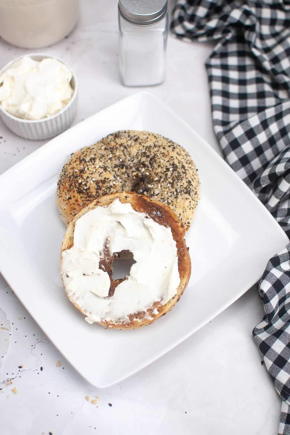 Sourdough bagels on a plate, topped with creamy spread and ready to eat.