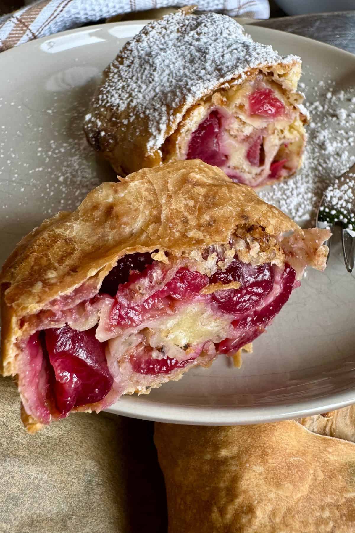 Close-up view of a cherry strudel, showing the flaky pastry layers and juicy cherry filling inside.