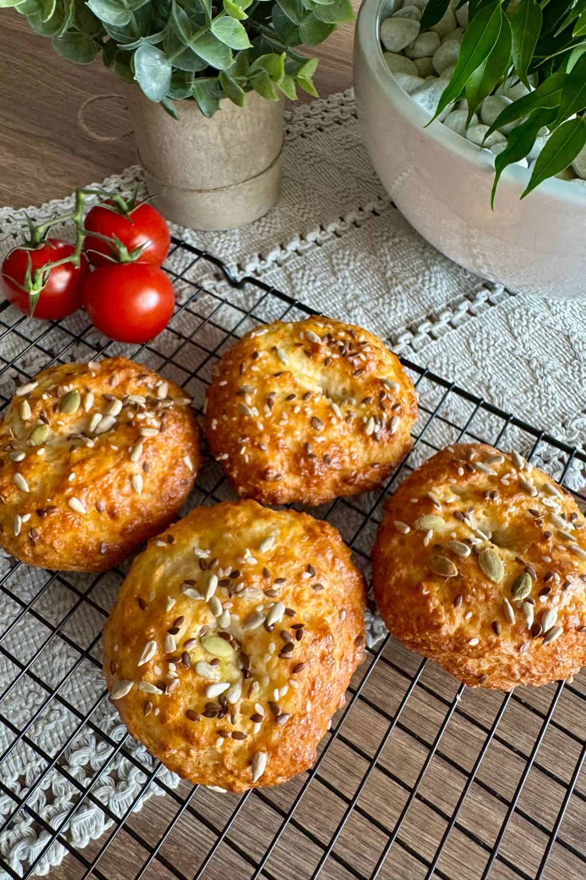 Close-up of protein bagels on a wire rack, topped with sesame seeds, highlighting their soft, chewy texture and golden-brown crust.