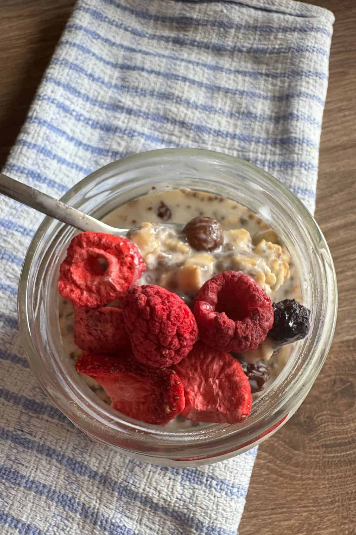 Overnight oats in a jar with visible berries, with a spoon resting on top.