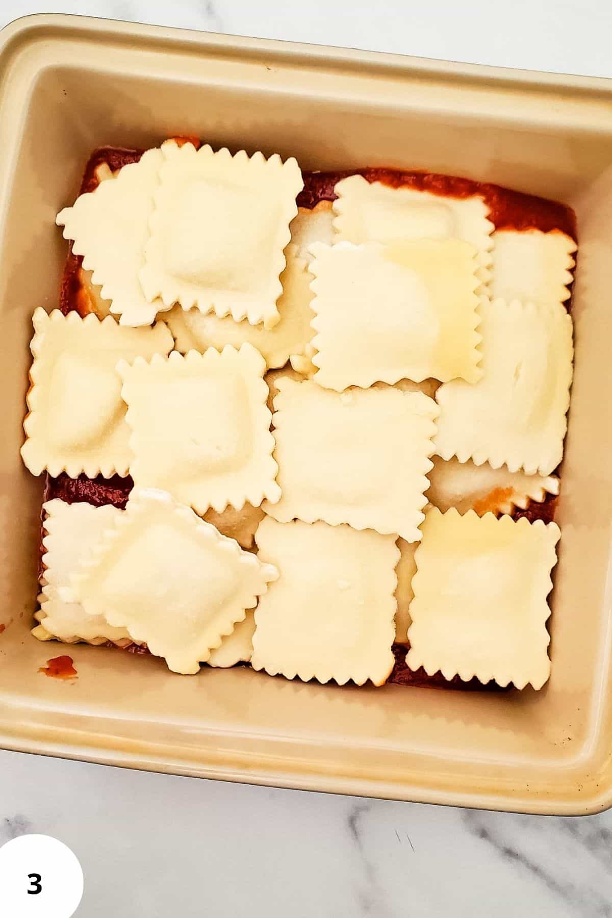 Layered ravioli lasagna in a casserole with ravioli visible on top.