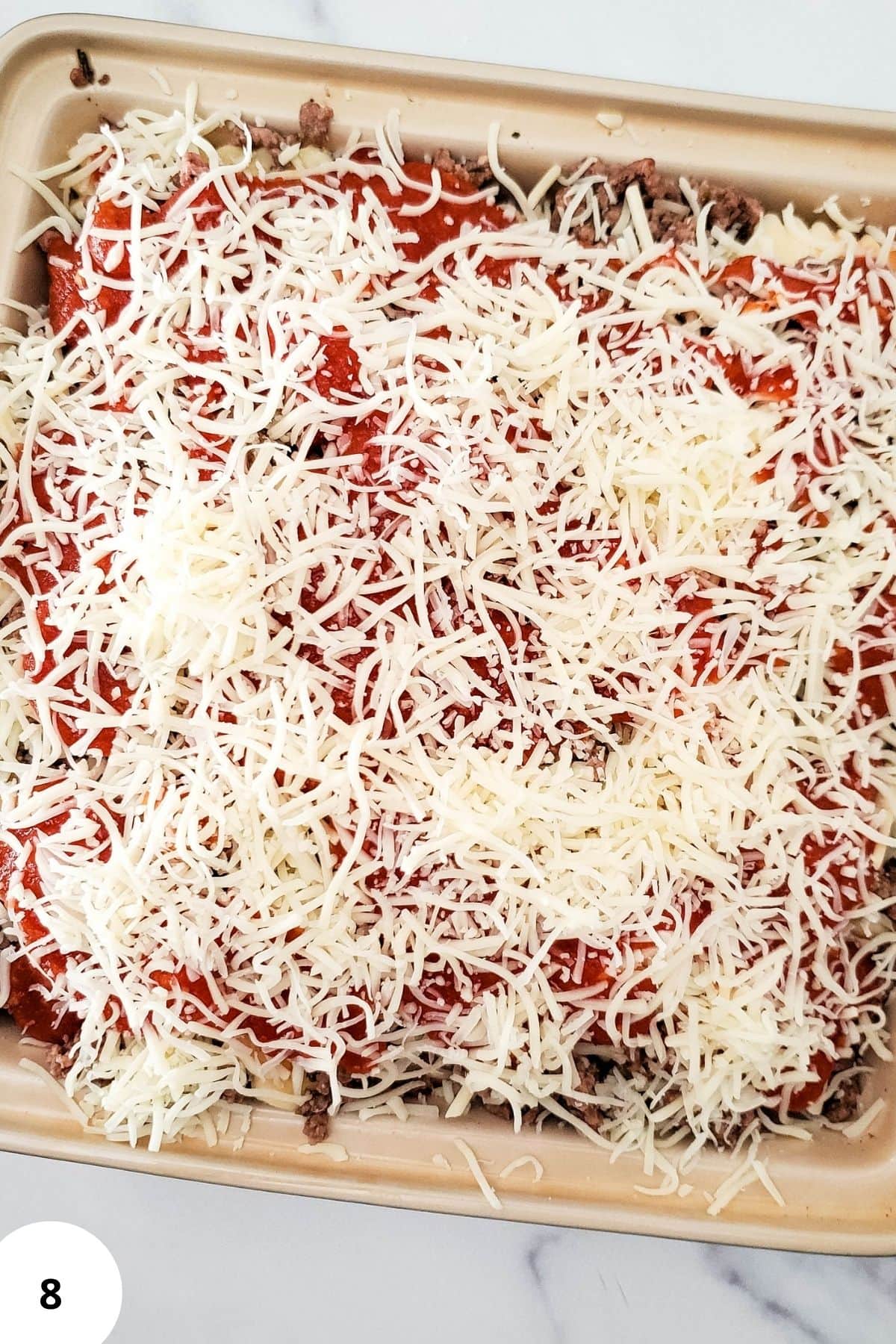 Layered ravioli lasagna in a casserole topped with melted cheese.