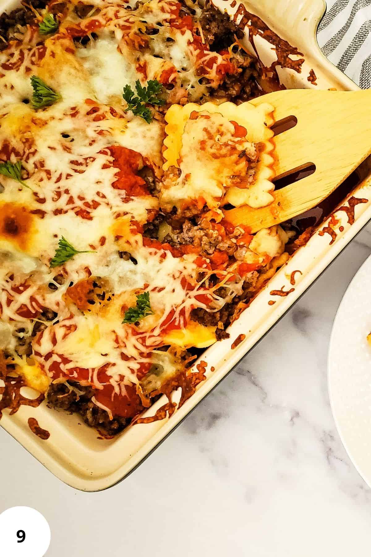Layered lasagna in a casserole with a spatula resting on top.