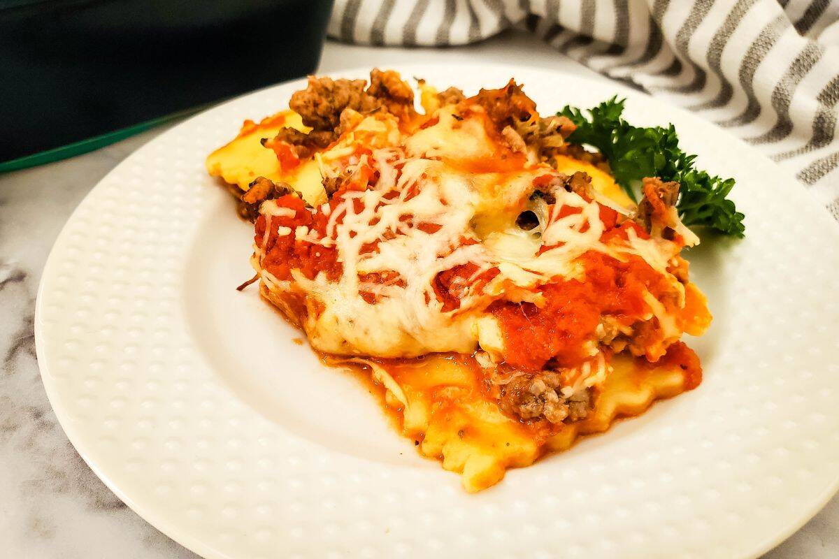 A plate of ravioli lasagna with the casserole and spatula beside it.