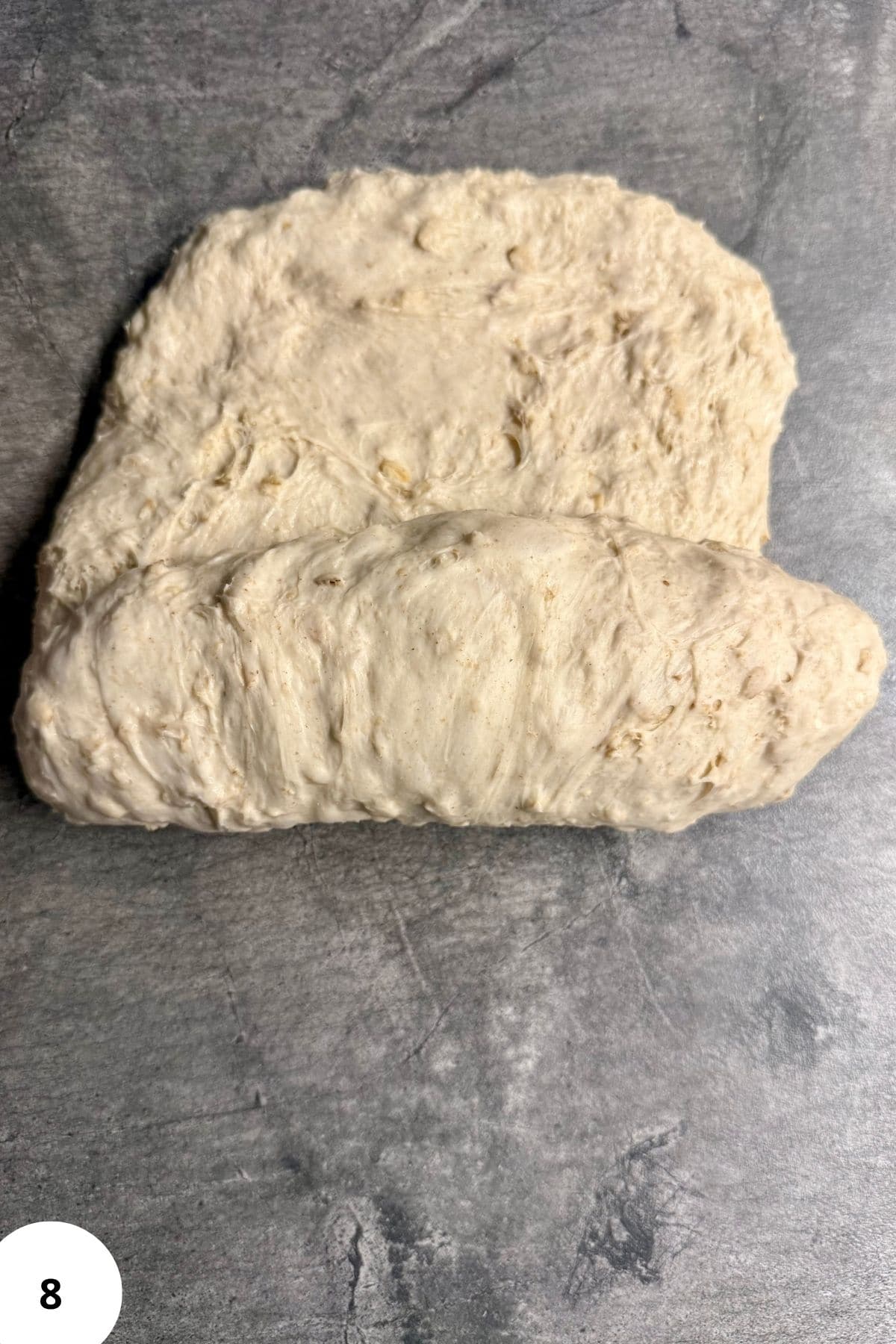 Dough being rolled on a smooth floured surface.