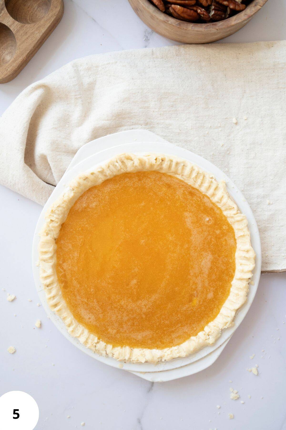 Unbaked pie crust filled with pecan mixture, ready to be baked.