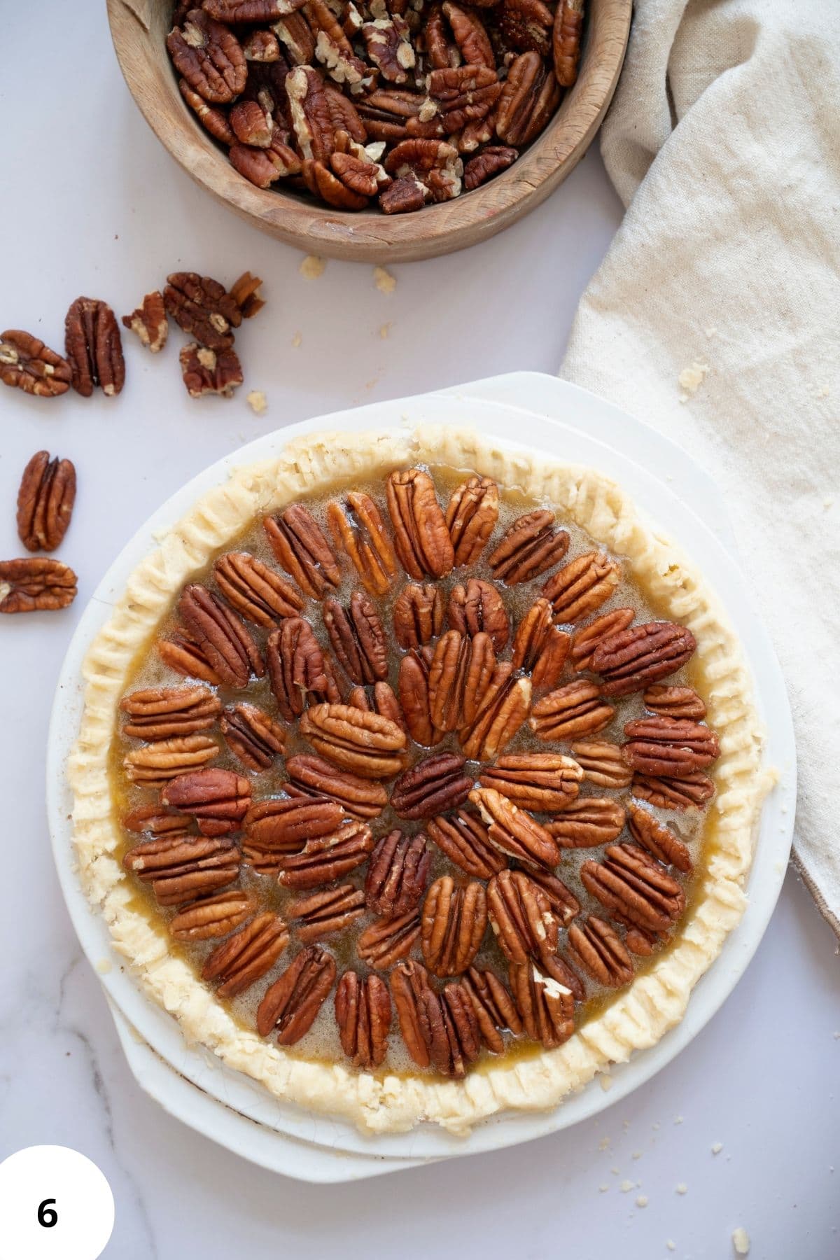 A whole pecan pie topped with pecans arranged neatly on the surface.