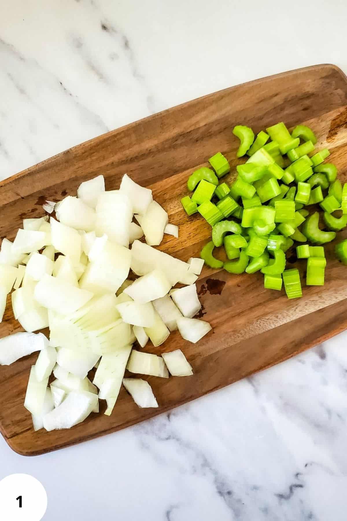 Diced onion and chopped parsley on a wooden chopping board.