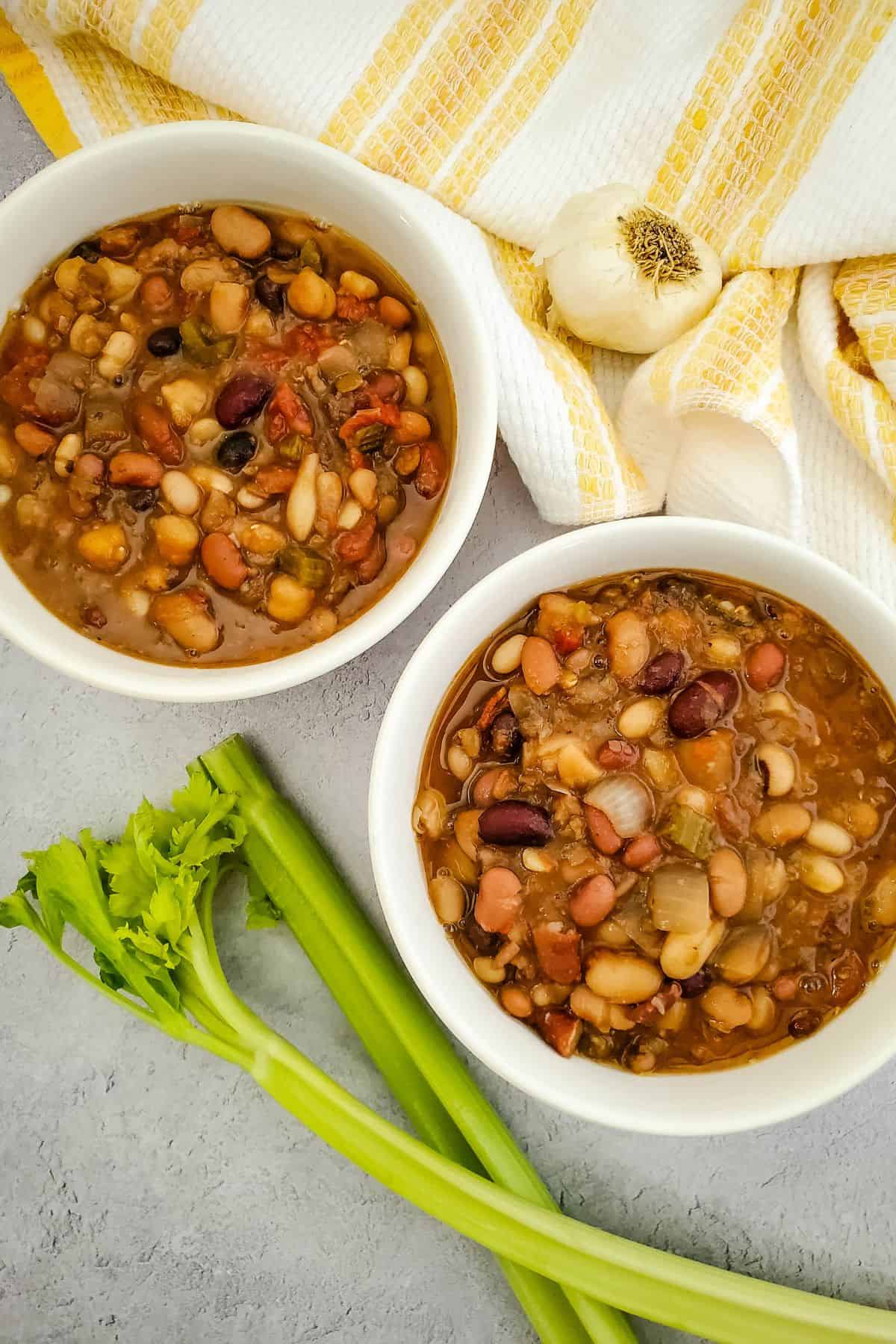 Bowls filled with vegan bean soup garnished with fresh parsley, with a table napkin placed beside them.
