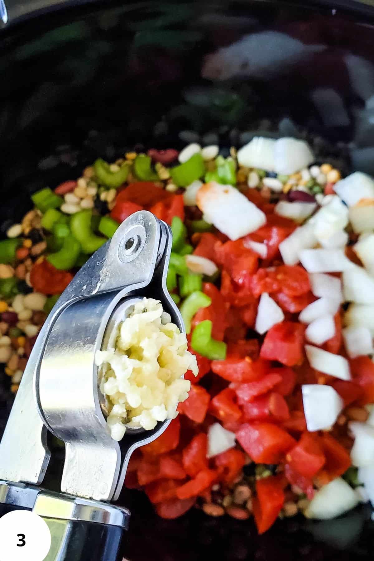 Ingredients mixed together in a crockpot, with minced garlic being added.