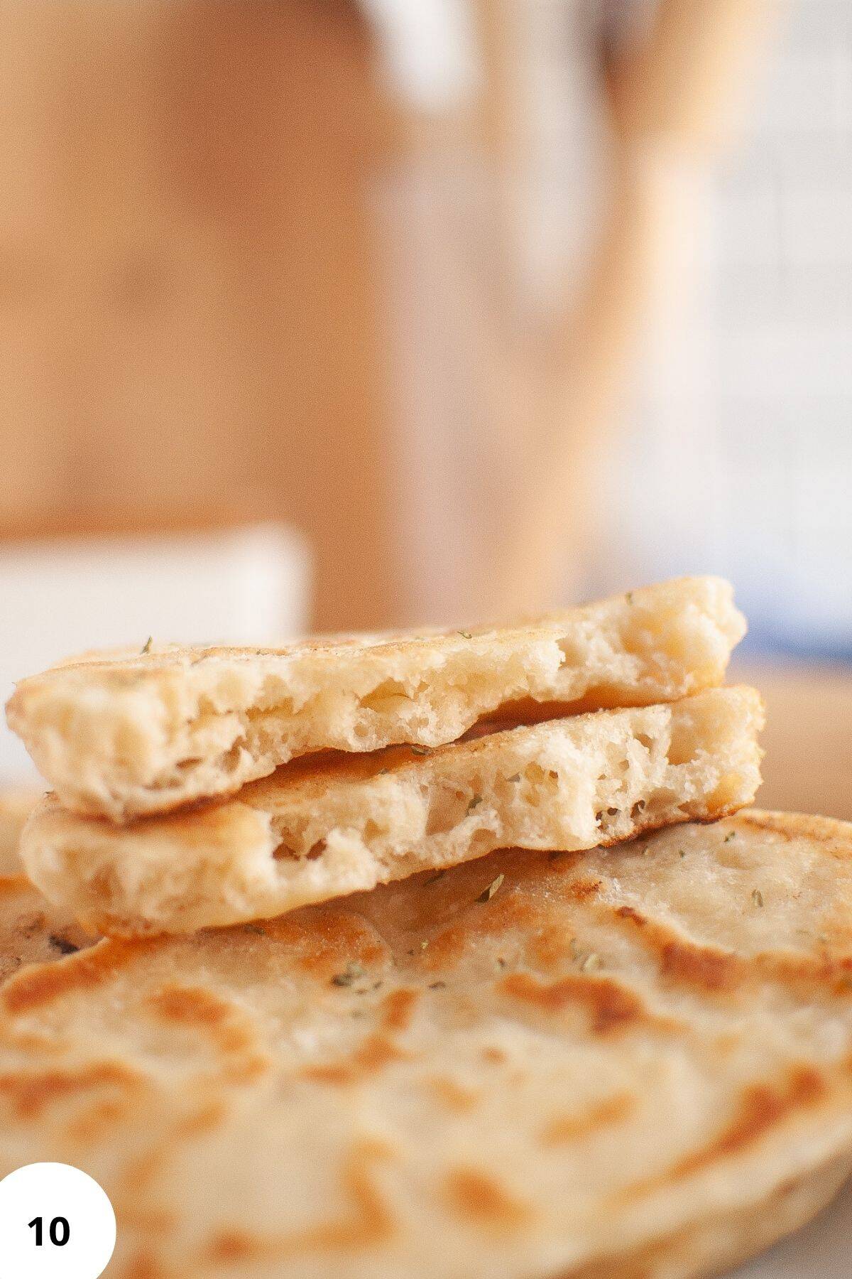 Stacked naan with a piece pulled apart to reveal the soft, pillowy interior.