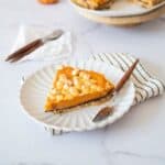 Slice of sweet potato pie on a plate with a table napkin underneath and a fork on the side.