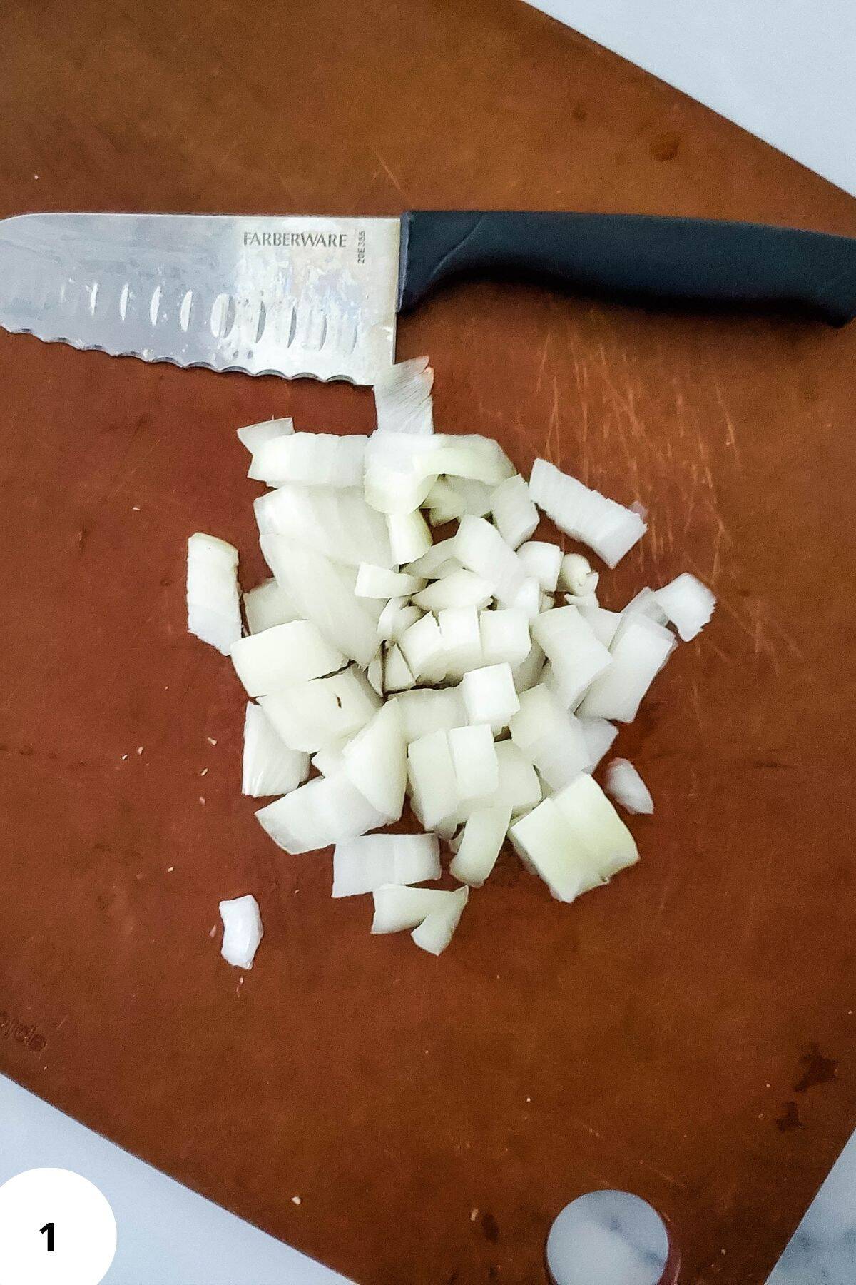 A chopping board with diced onion and knife.