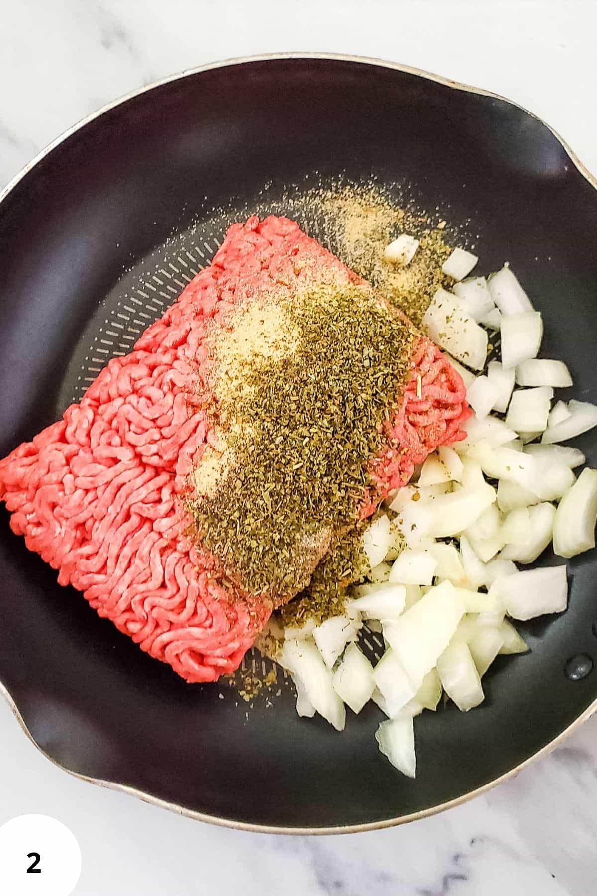 Ground beef and onion being seasoned in a pot.