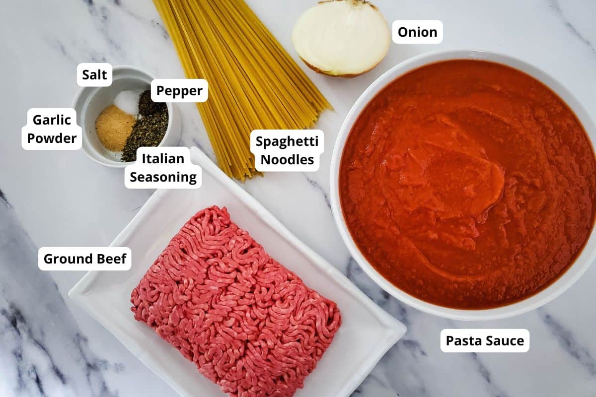 Ingredients for spaghetti with meat sauce arranged on a countertop.