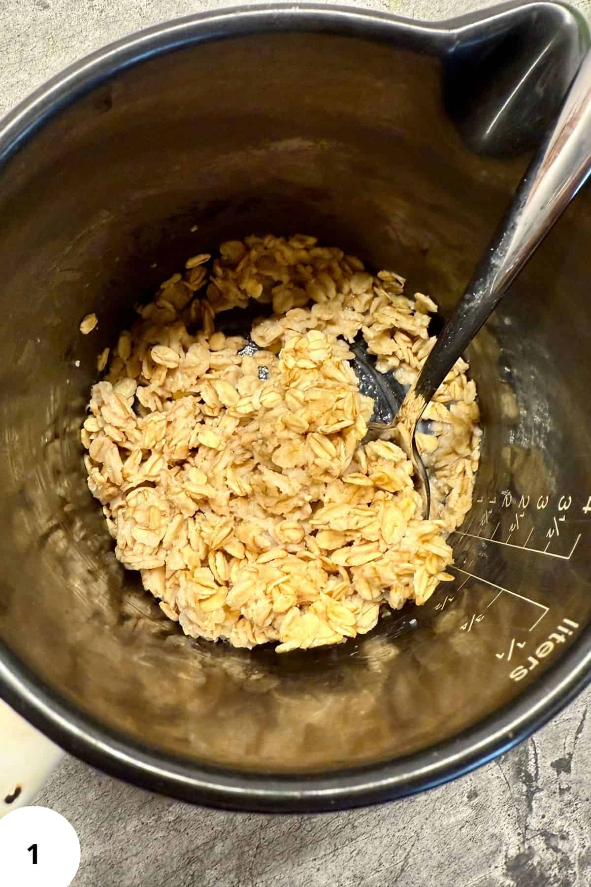 Cooked oats in a bowl with a spoon resting on top.