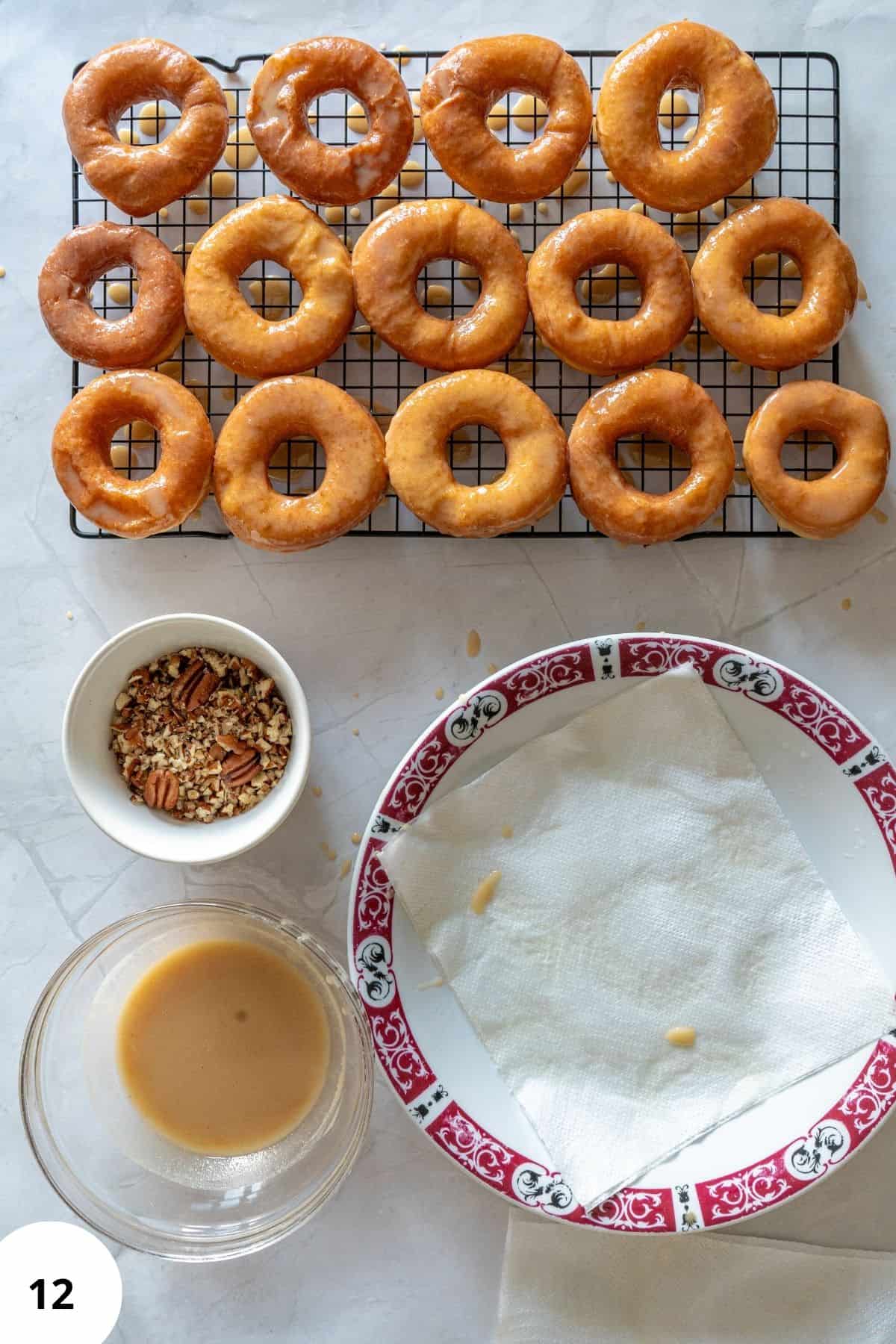 Donuts on a wire cooling rack being topped with maple glaze.