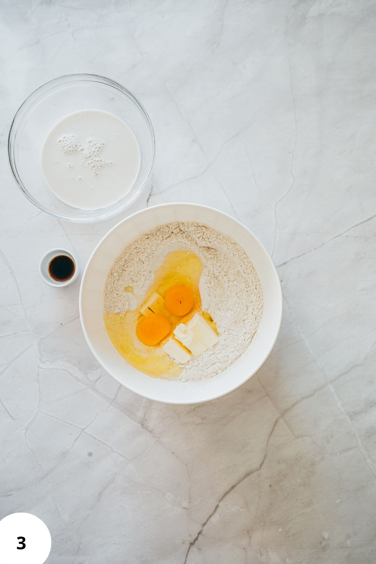 Donut ingredients being mixed in a large bowl surrounded by other baking ingredients.