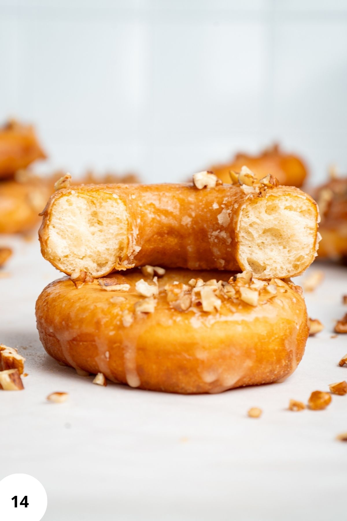 Stacked maple glazed donuts with the top donut showing its soft, airy inside.