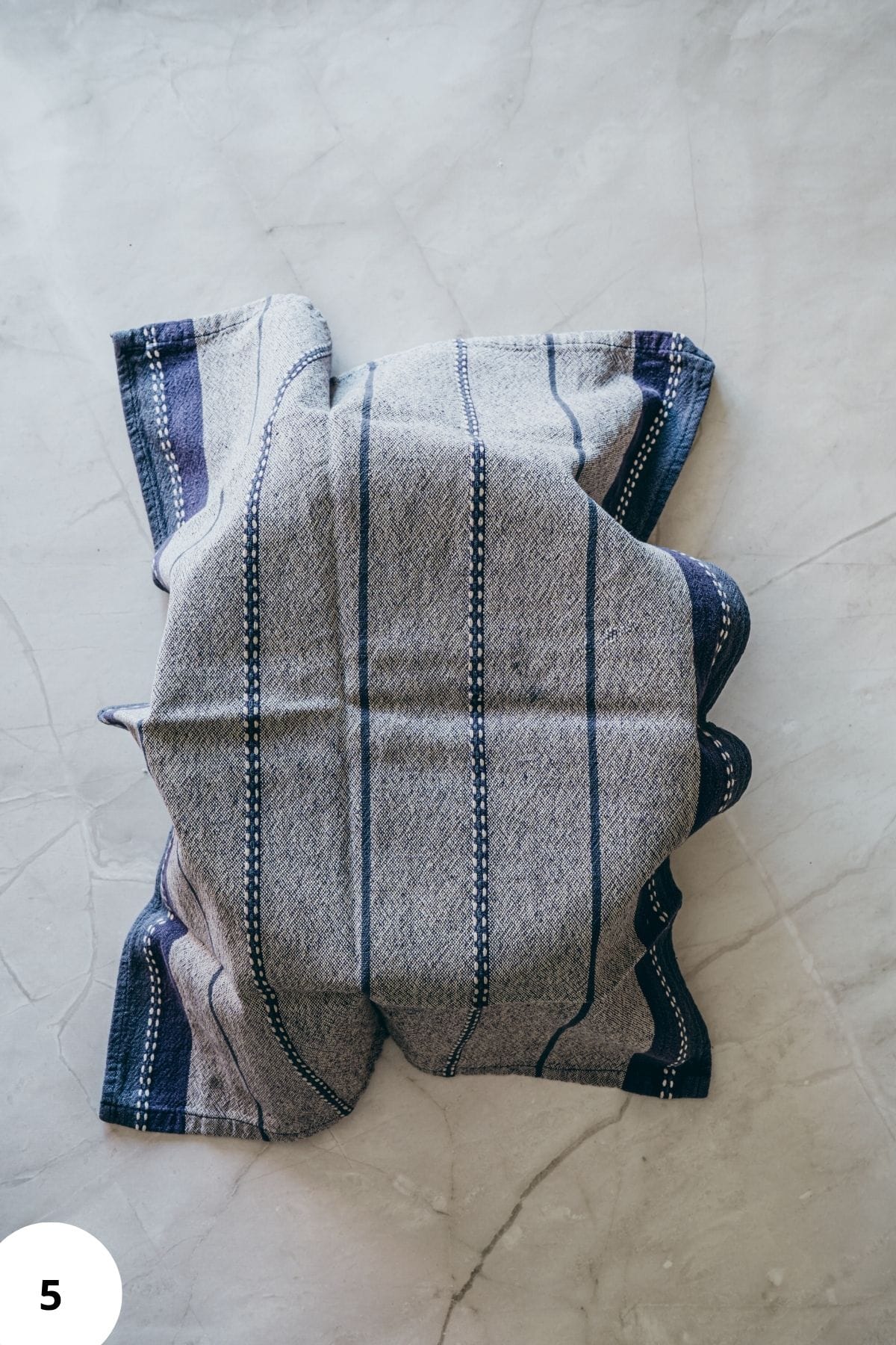 Bowl of donut dough being covered with a cloth for rising.