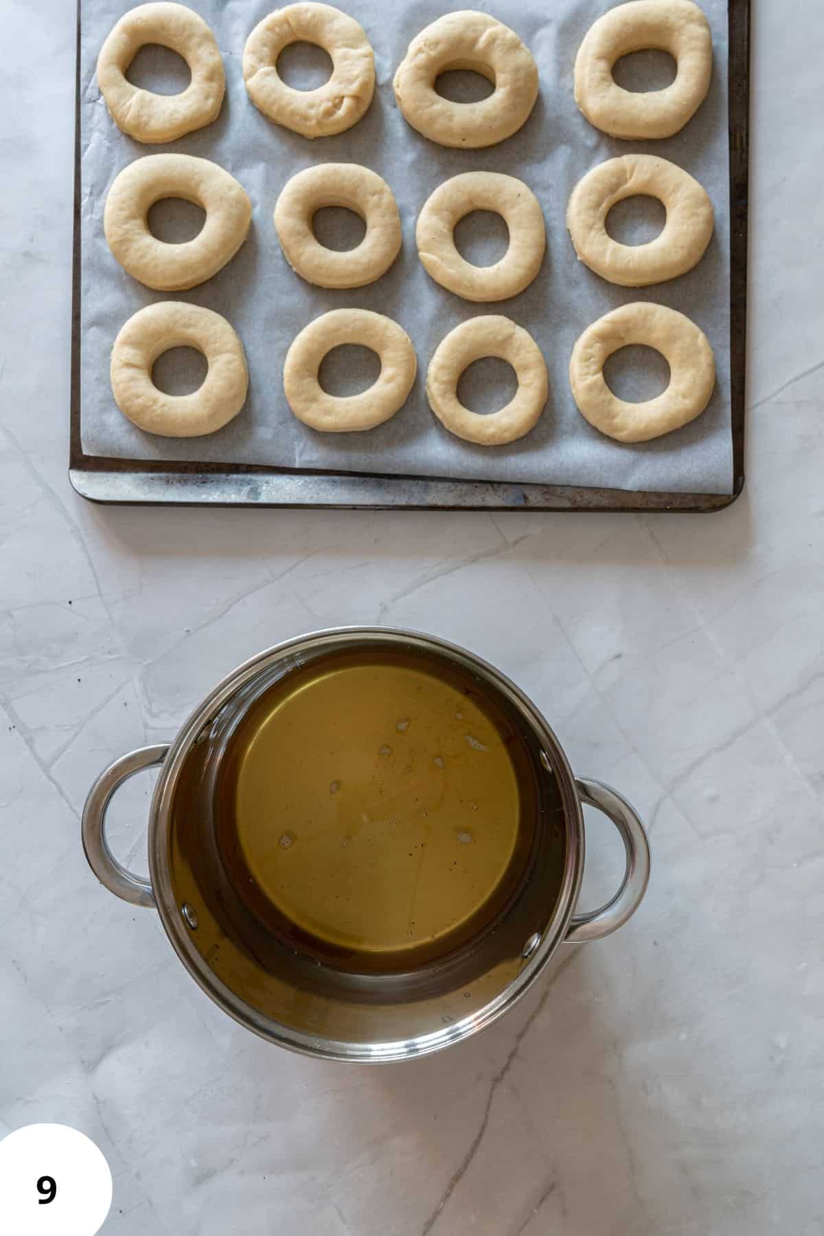 Pot of hot oil with freshly fried donuts resting on a wire rack.