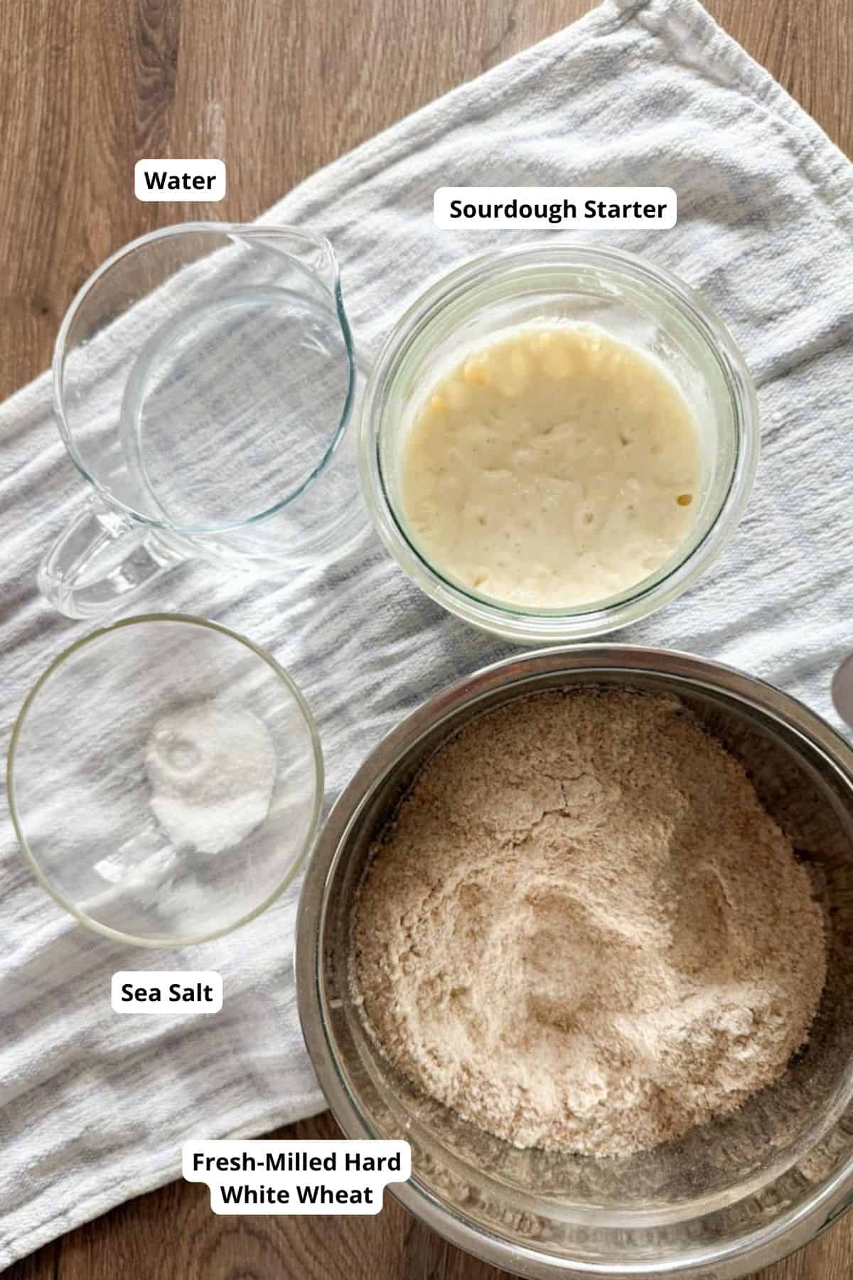 Ingredients for sourdough arranged on a surface with a table napkin underneath.