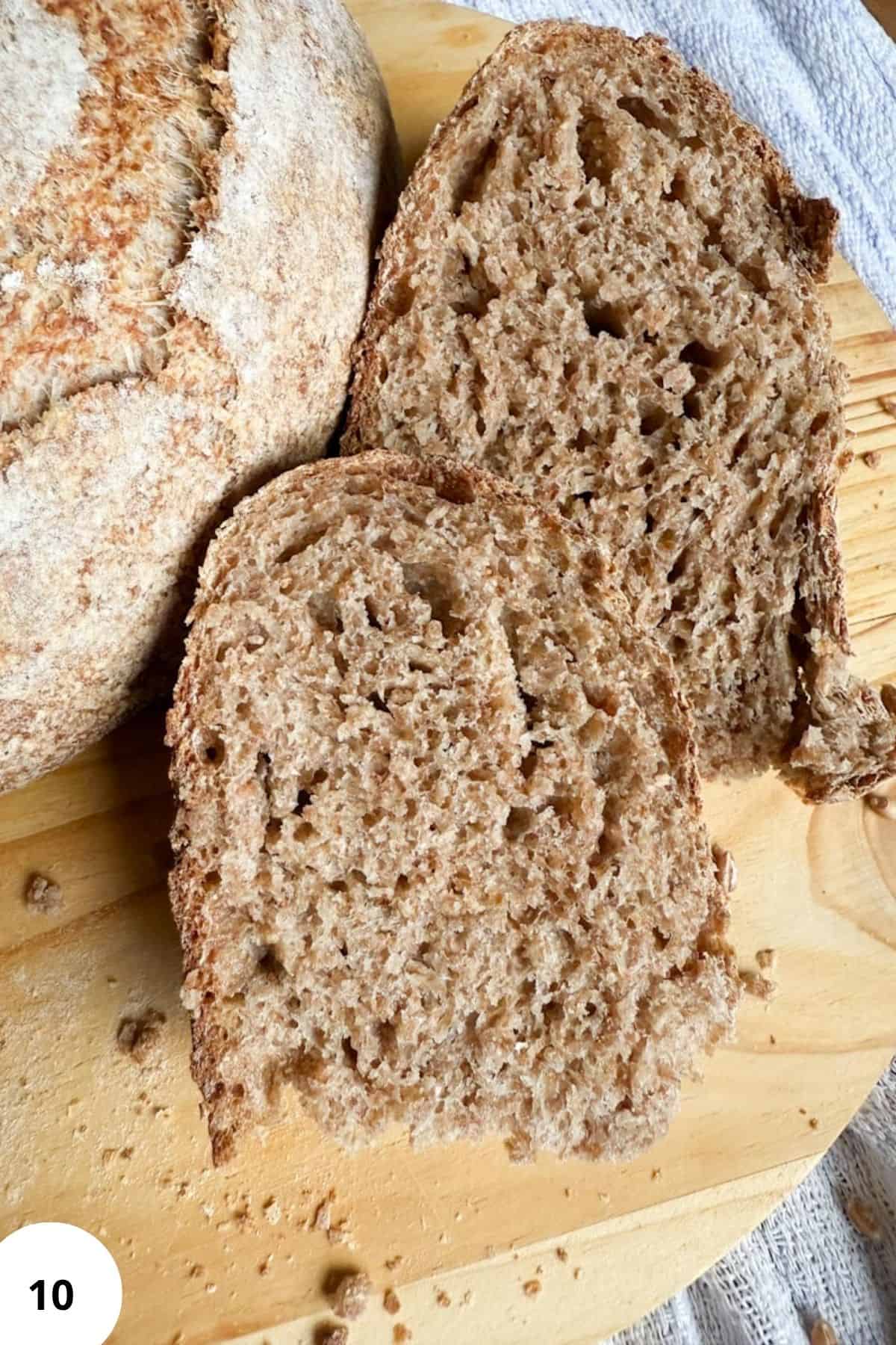 Freshly baked sourdough loaf sliced and resting on a rustic wooden board.