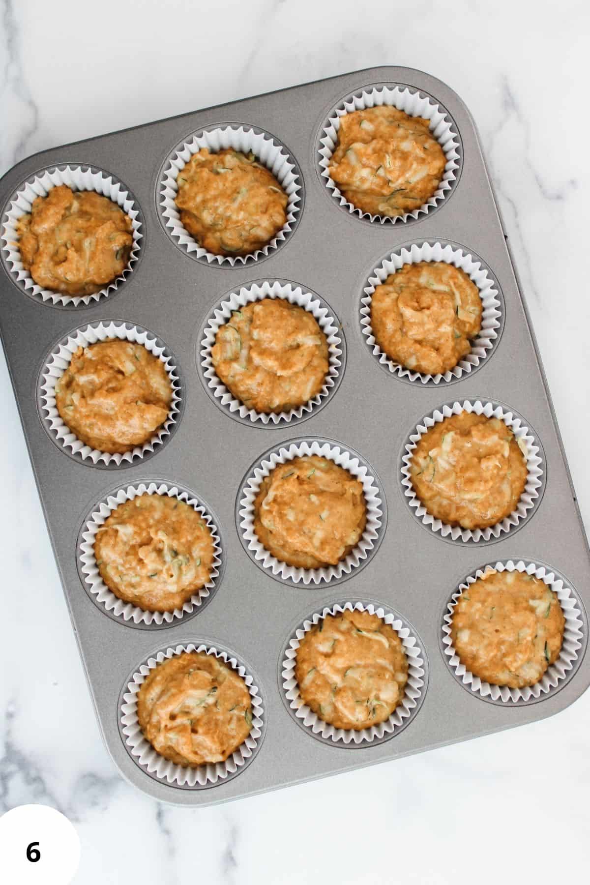 Scooped pumpkin zucchini muffin batter placed in a baking pan, ready to bake.