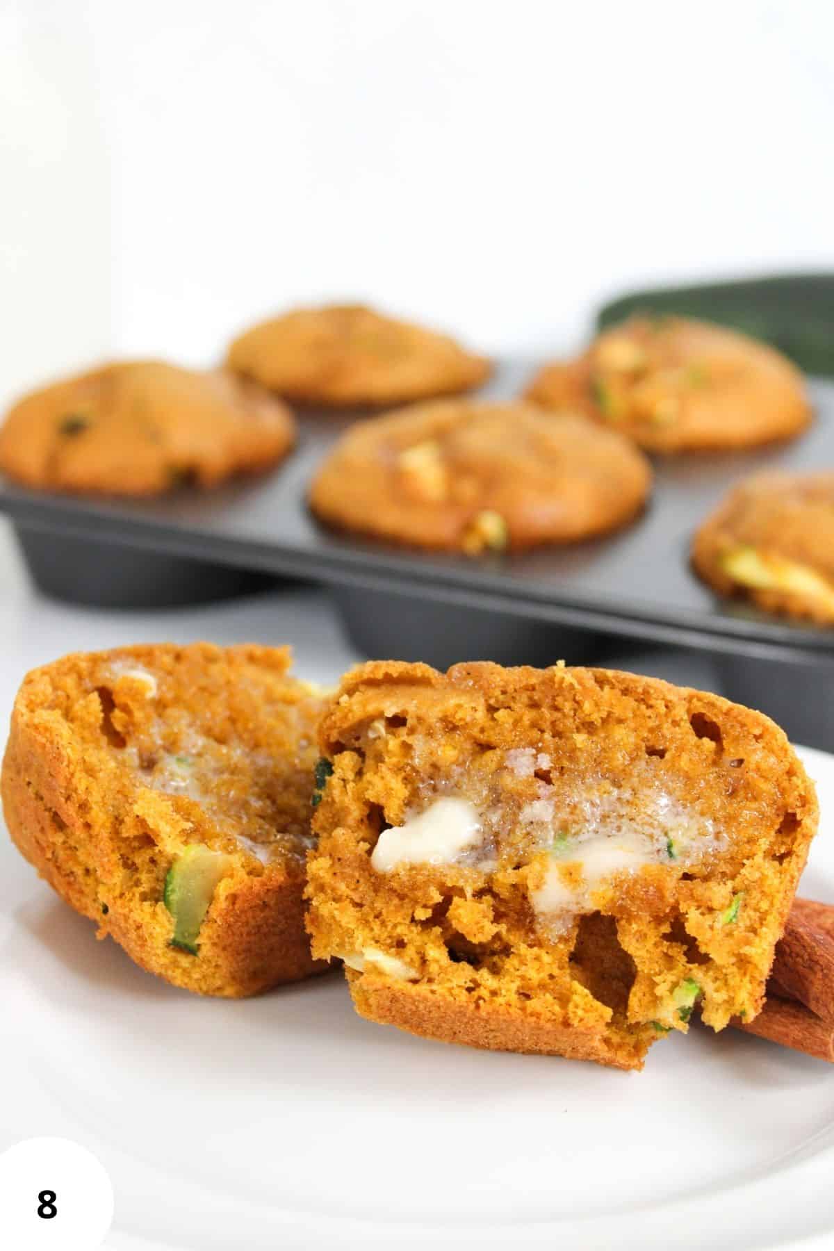 Close-up of a pumpkin zucchini muffin showing the soft, moist interior with visible zucchini and pumpkin pieces.