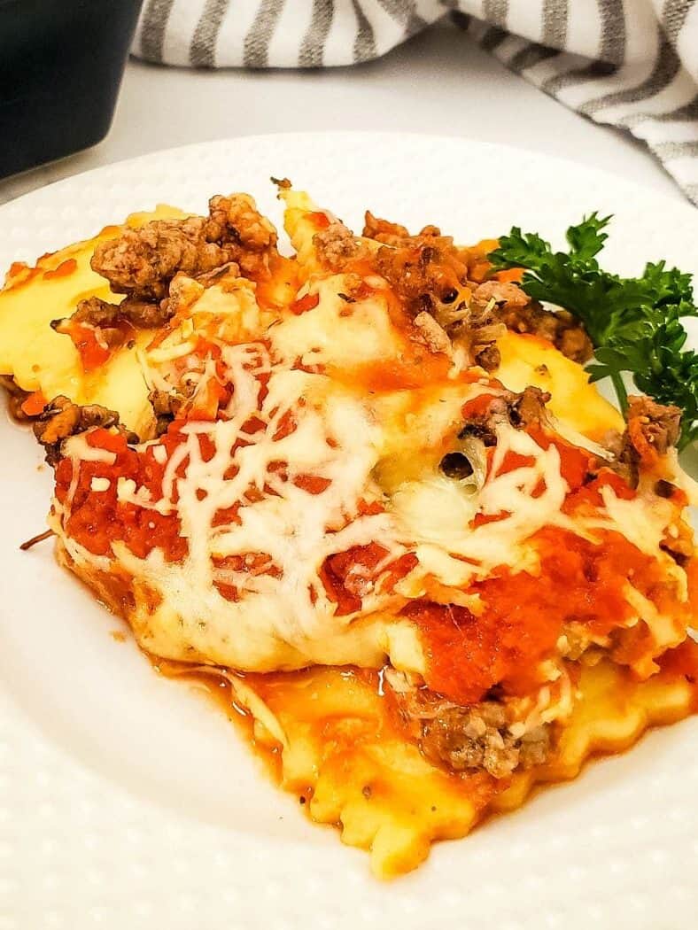A plate of ravioli lasagna with the casserole and spatula beside it.