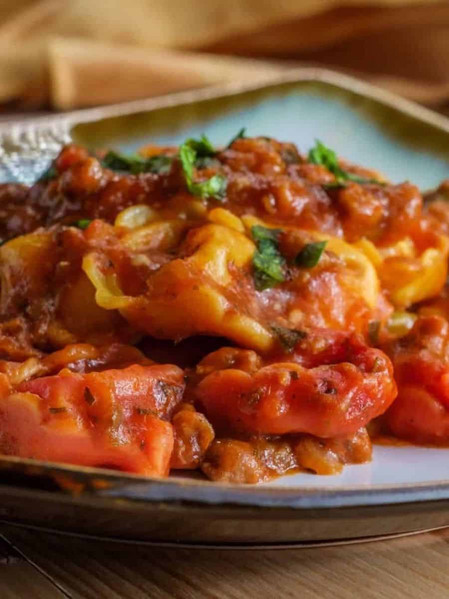 Close-up of freshly baked stuffed pasta with tomato sauce and herbs.