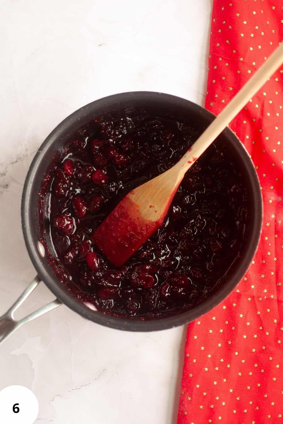 Cranberry mixture in a saucepan with a spatula resting on it.