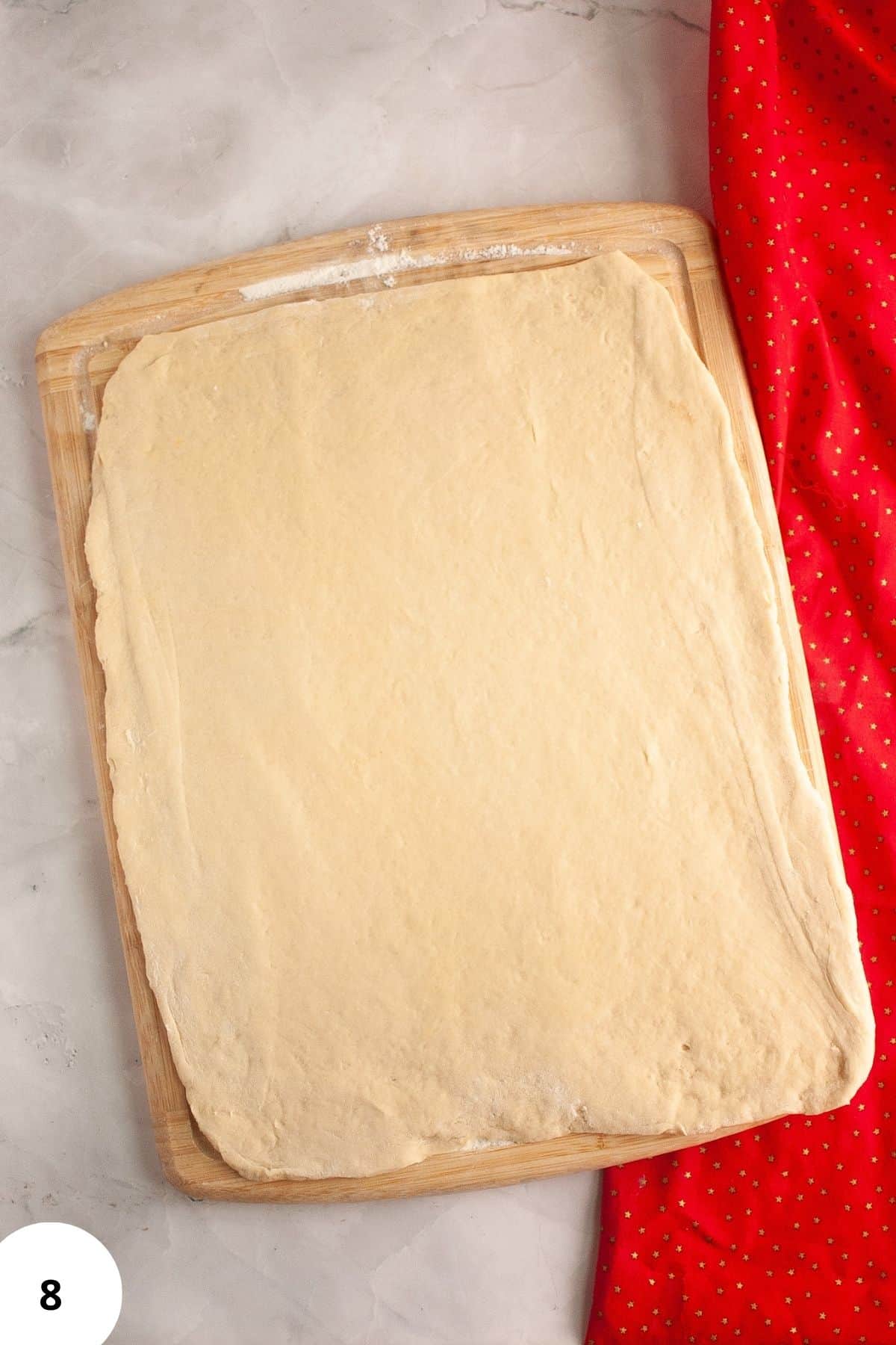 Flattened dough on a wooden board.