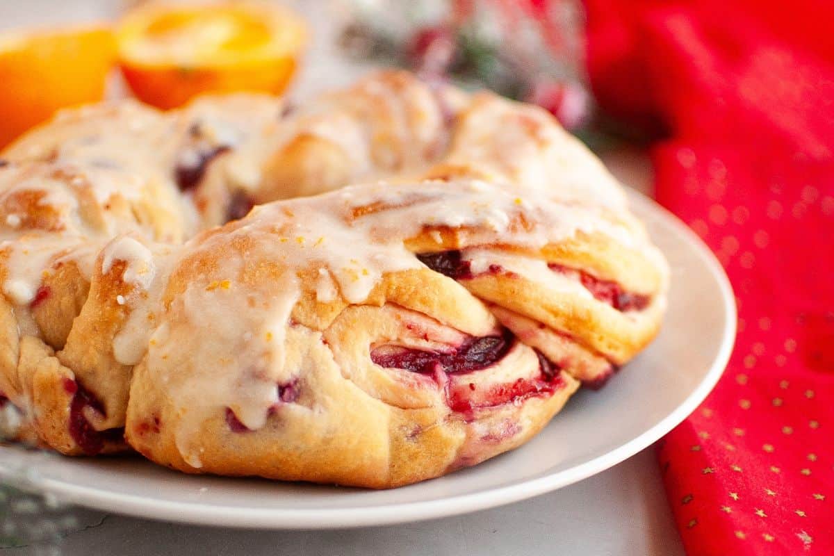 Closer look of cranberry bread on a plate with Christmas ornaments around it.