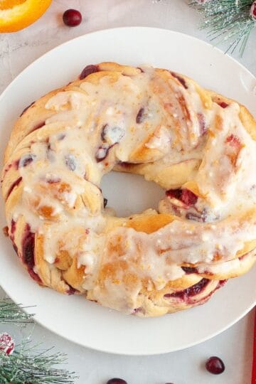 Cranberry bread on a plate with Christmas ornaments around it.