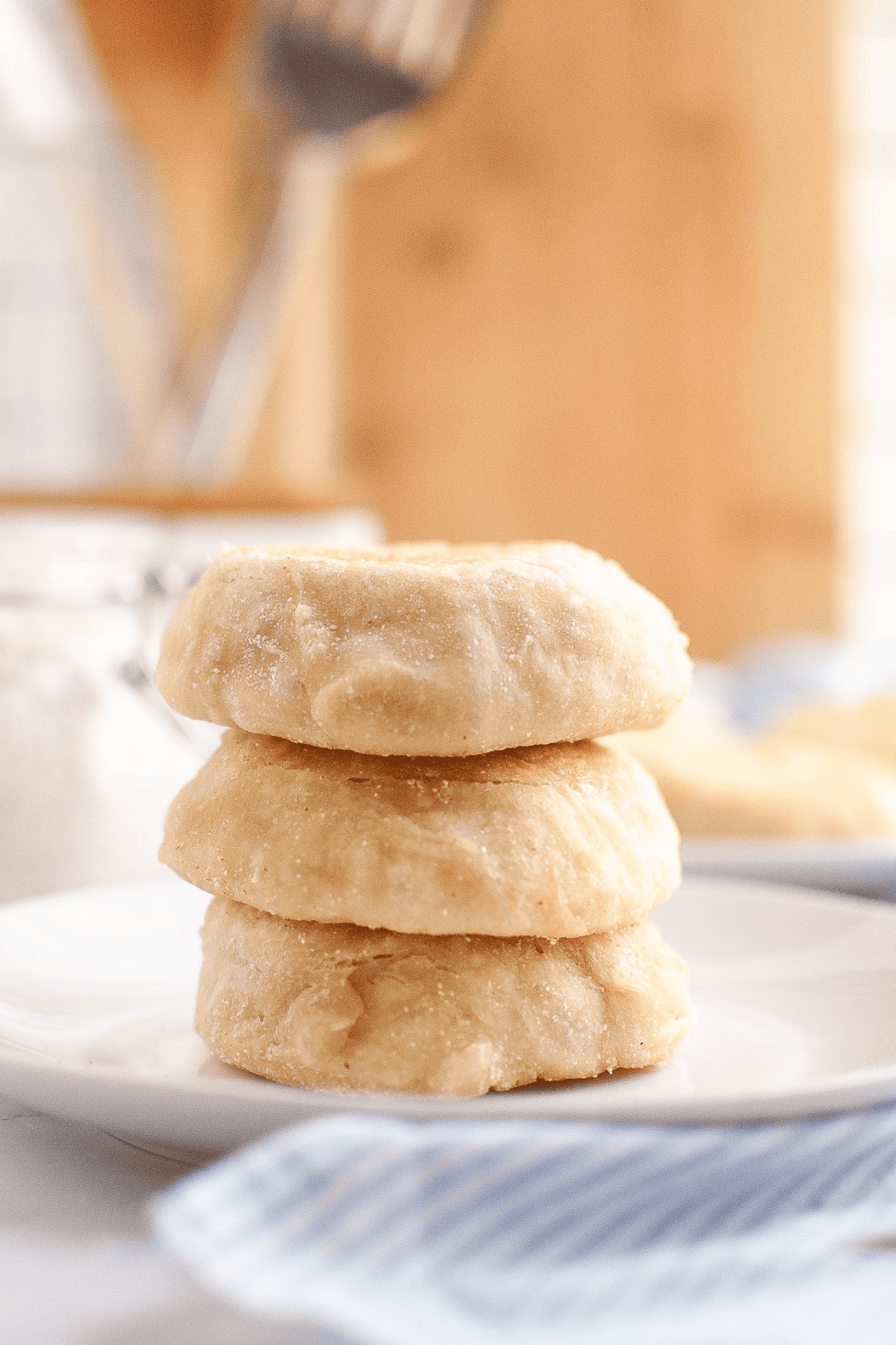 A stack of soft, golden-brown English muffins served on a plate, showing their fluffy texture and lightly crisp edges.