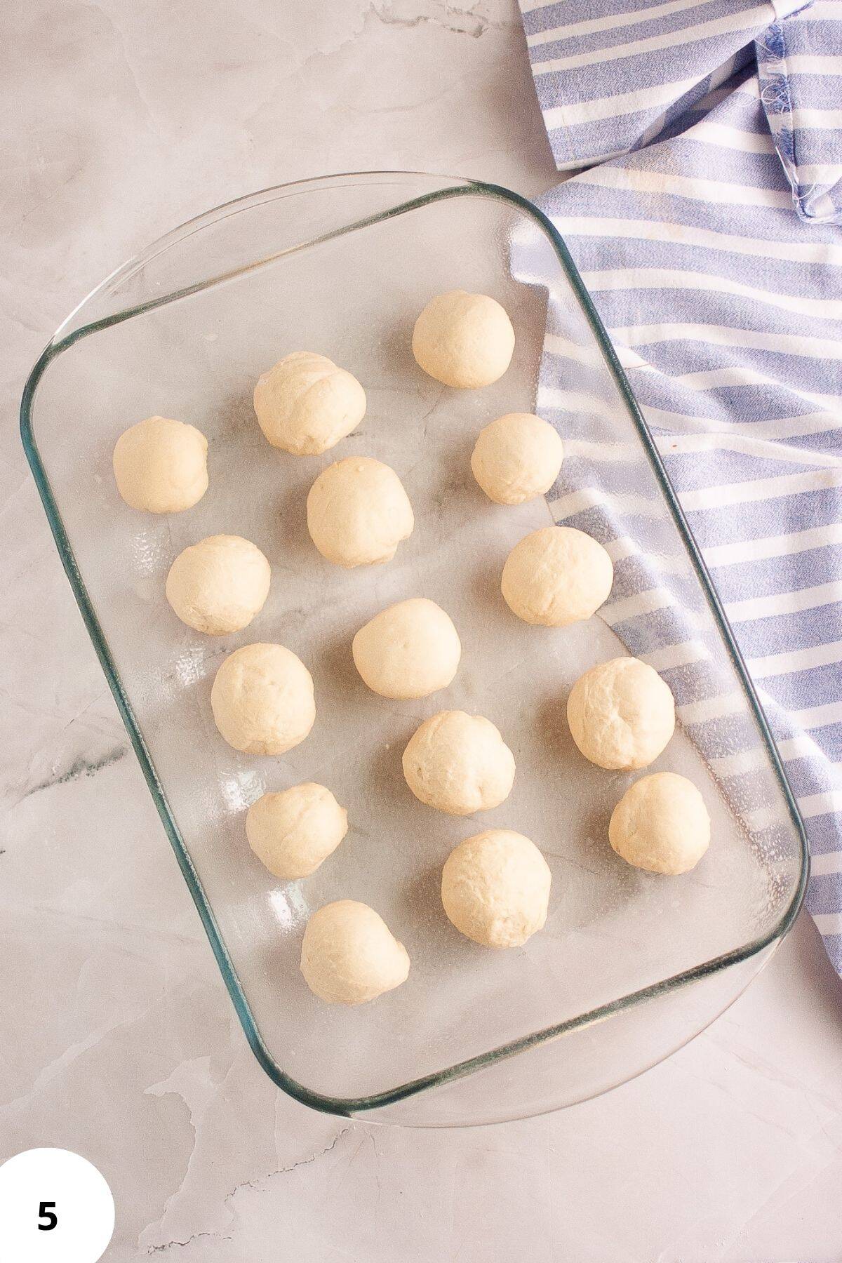 Sourdough brioche rolls placed in a baking dish with space between them, ready for proofing or baking.