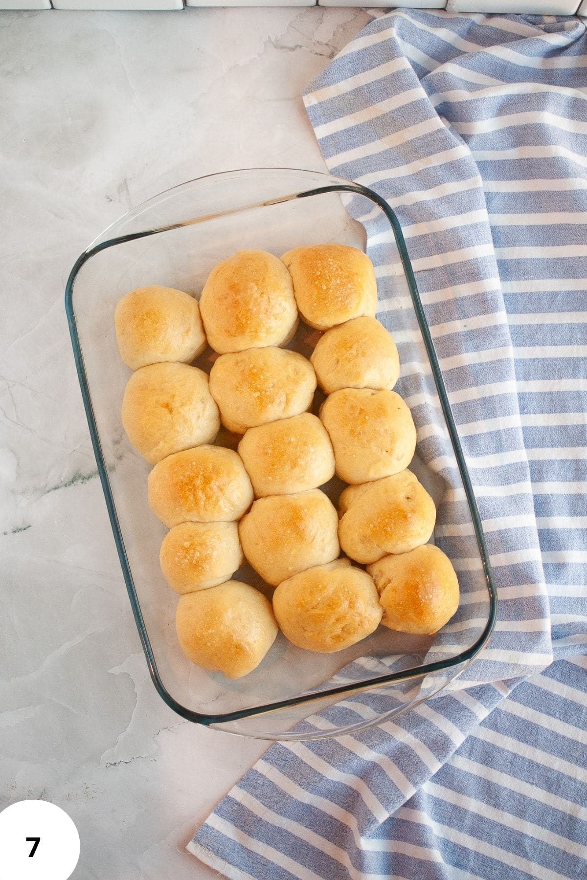A baking dish filled with freshly baked sourdough brioche rolls, golden and puffed.